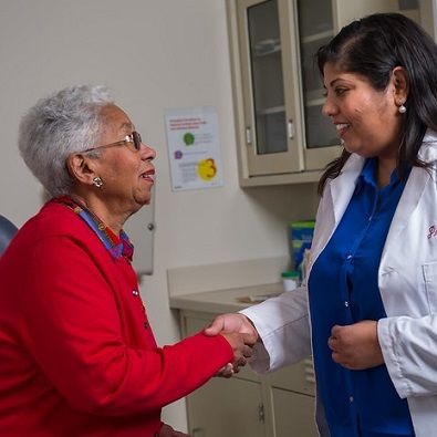 A doctor shaking hands with an elderly woman.